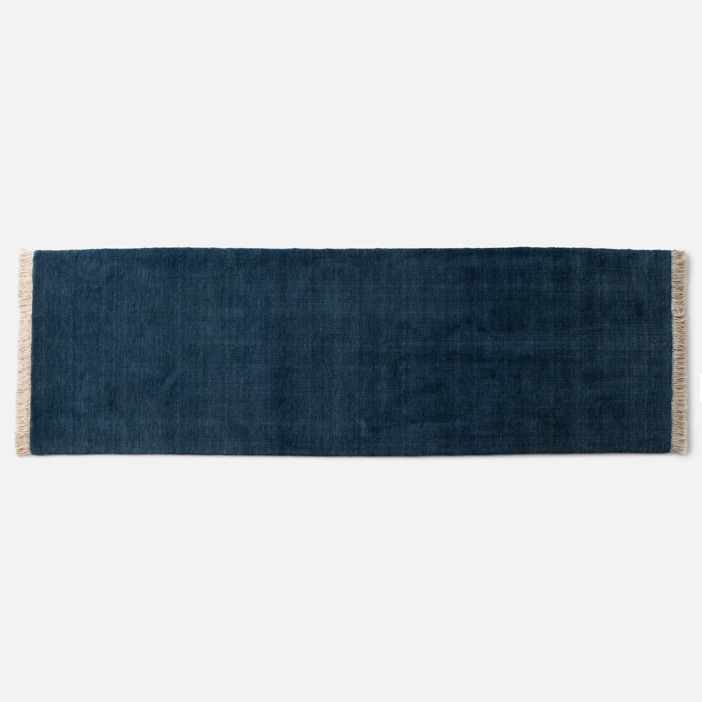 Top edge view of Mesa Wool Rug showcasing hand-loomed New Zealand wool pile and natural fringe on a white background