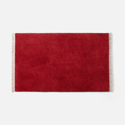 Top-down view of Mesa Wool Rug in red showcasing hand-loomed cut pile and cream fringe on white background