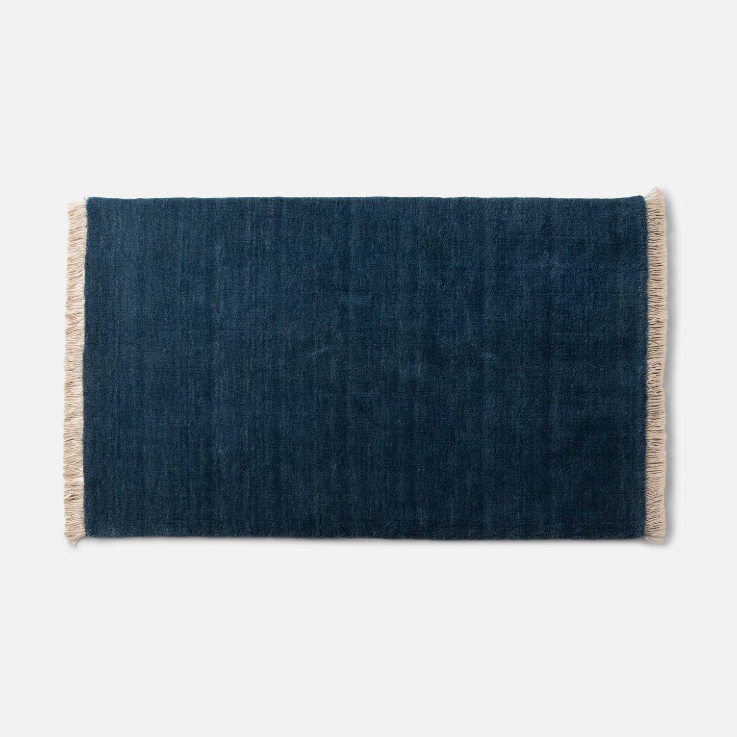 Cropped top view of Mesa Wool Rug showcasing hand-loomed New Zealand wool pile and cream fringe on white background