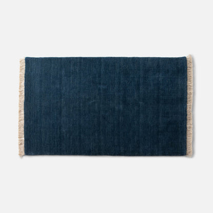 Cropped top view of Mesa Wool Rug showcasing hand-loomed New Zealand wool pile and cream fringe on white background