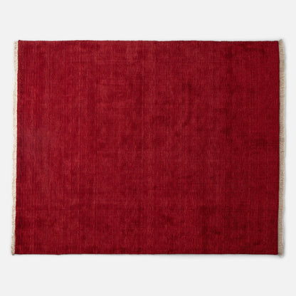 Top edge view of Mesa Wool Rug showcasing red hand-loomed wool pile and natural fringe on a white background