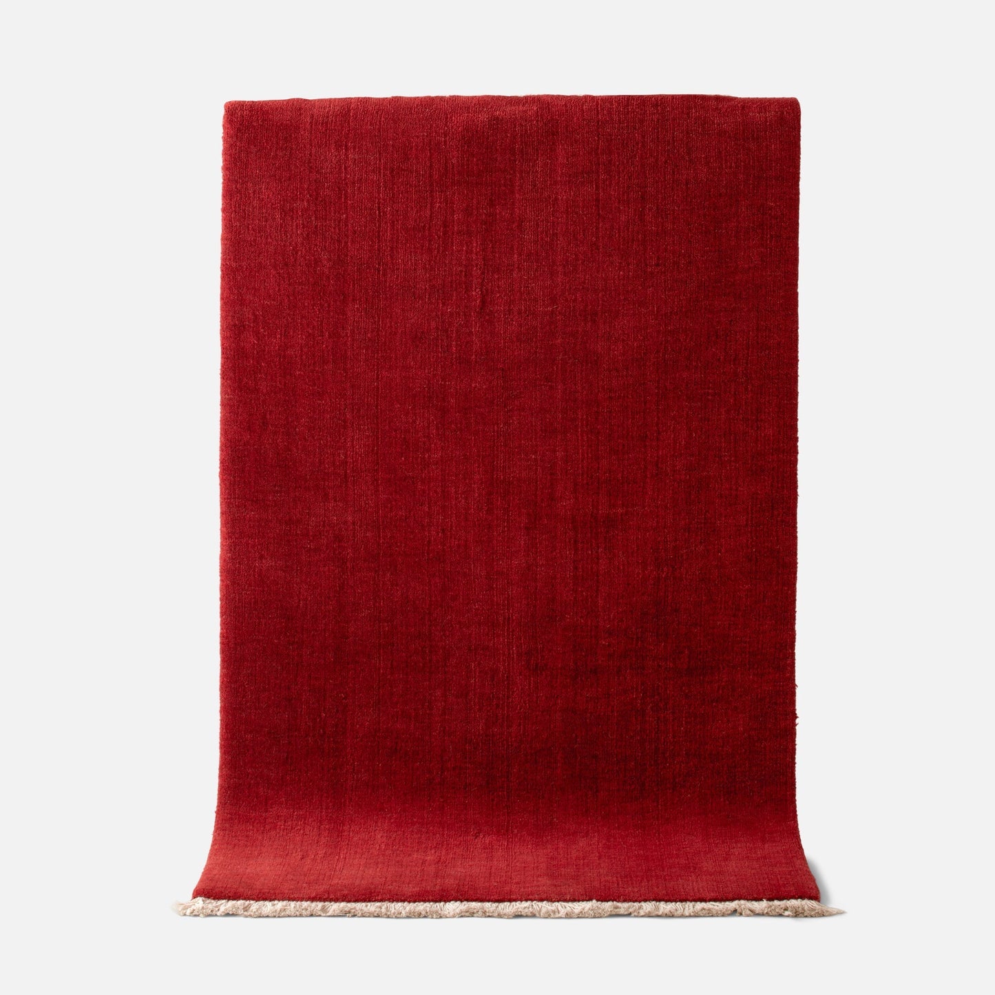 Top edge view of Mesa Wool Rug in Currant showing hand-loomed New Zealand wool cut pile texture and fringe on a white background