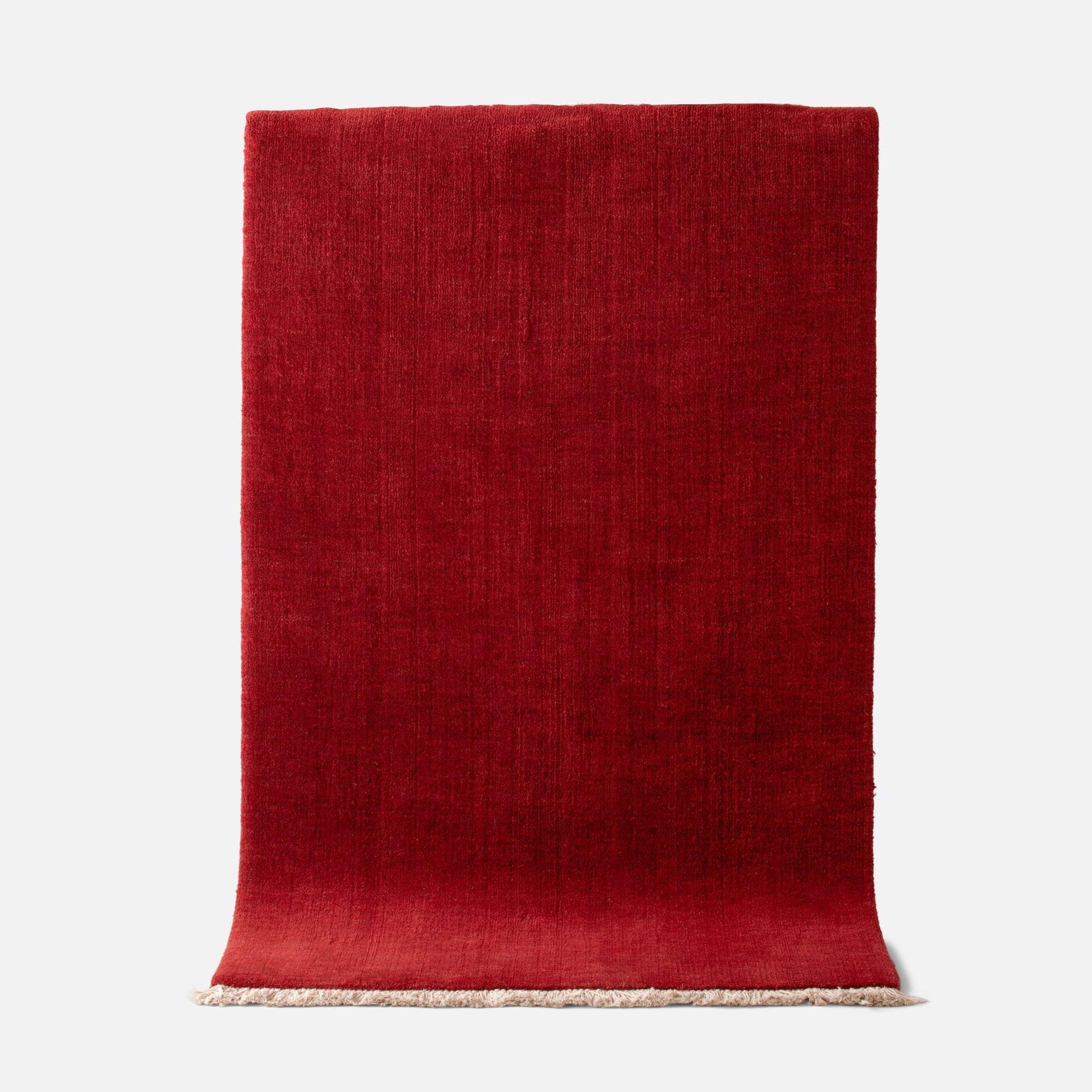 Top edge view of Mesa Wool Rug in Currant showing hand-loomed New Zealand wool cut pile texture and fringe on a white background
