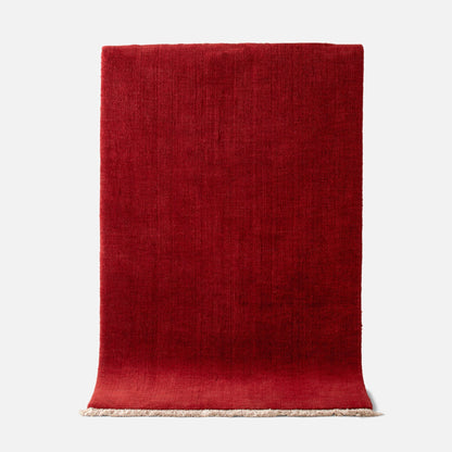Top edge view of Mesa Wool Rug in Currant showing hand-loomed New Zealand wool cut pile texture and fringe on a white background