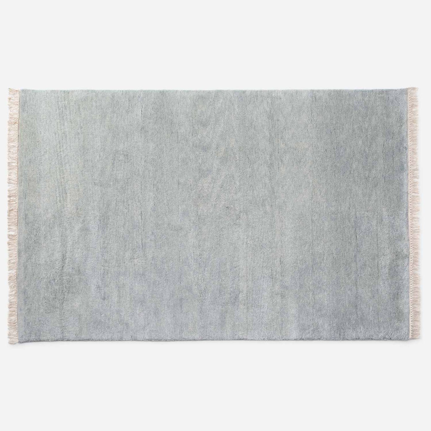 Top-down view of Mesa Wool Rug showcasing hand-loomed cut-pile New Zealand wool and natural fringe on a white background