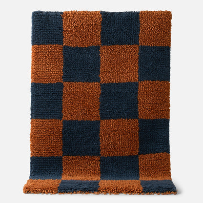 Close-up of Schoolhouse x Clare V Jacques shag wool rug showing navy and rust checkerboard with fringe