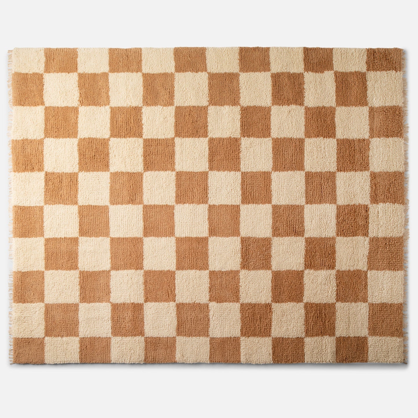 Top-down view of Jacques shag wool rug showing cream and tan checkerboard pattern, high-pile texture and fringe on white background