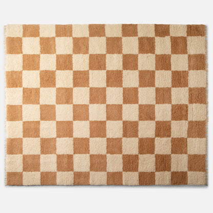 Top-down view of Jacques shag wool rug showing cream and tan checkerboard pattern, high-pile texture and fringe on white background