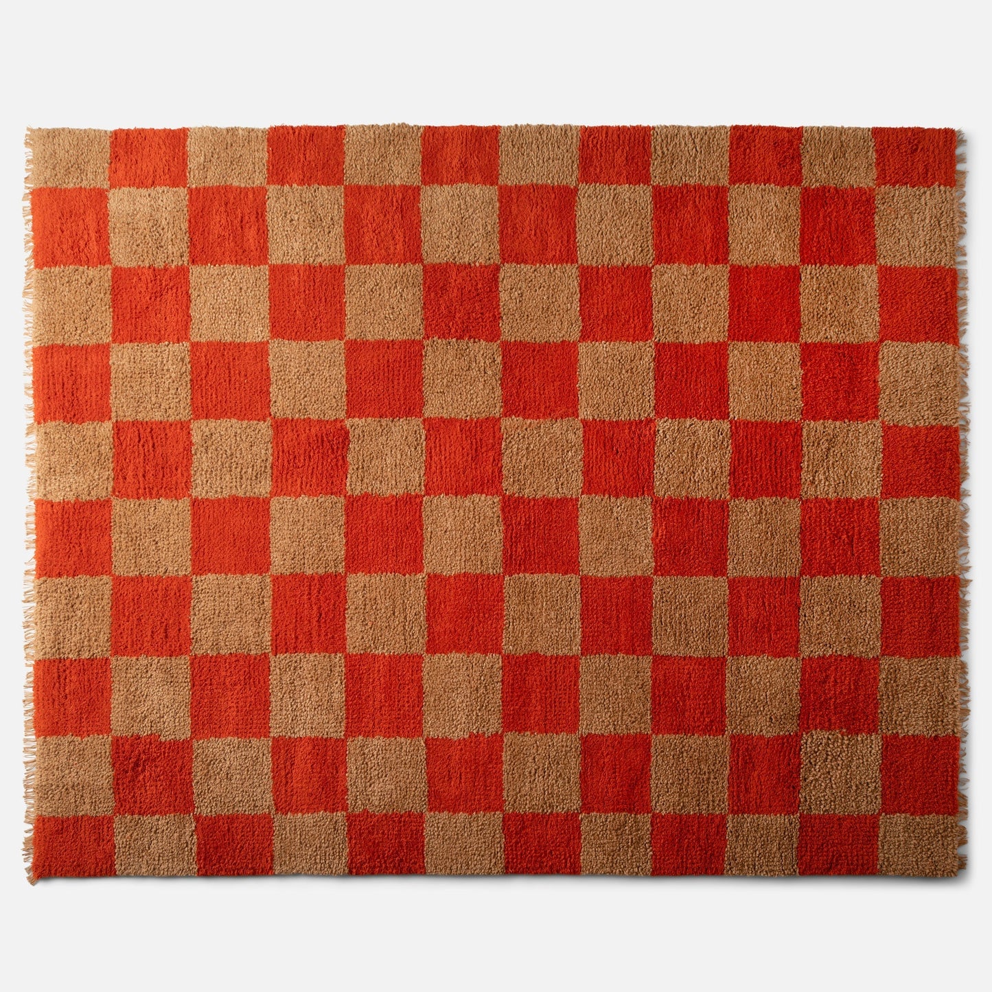Top view of Jacques Shag Wool Rug showcasing orange-and-tan checkerboard, high-pile shag texture and fringe on white background