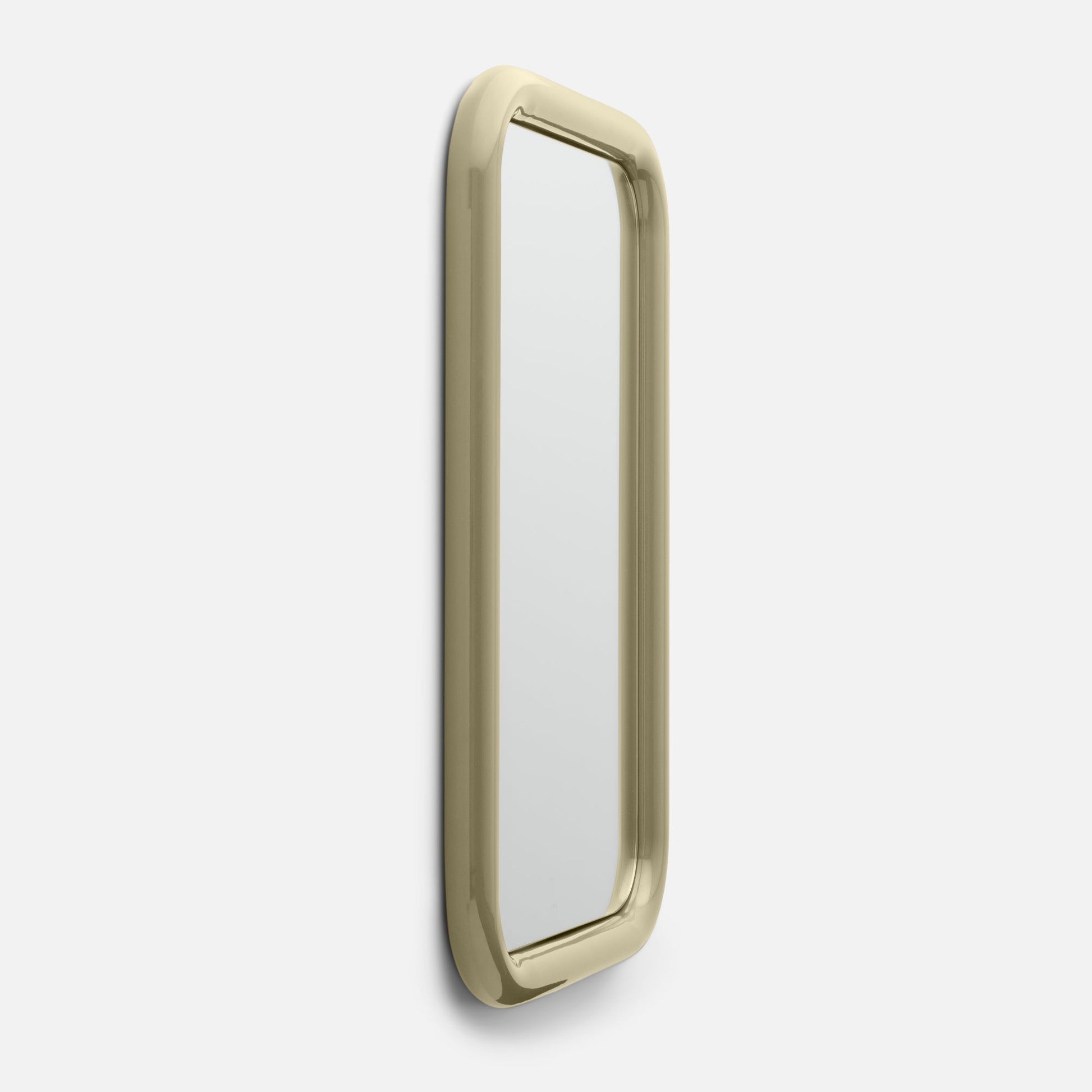 Close-up angled view of Forma Mirror showcasing rounded polished brass frame and narrow vertical mirror against a white background