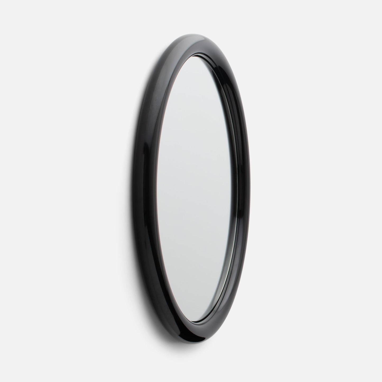 Close-up side view of Forma Mirror showcasing its glossy black rounded frame and beveled edge against a white wall
