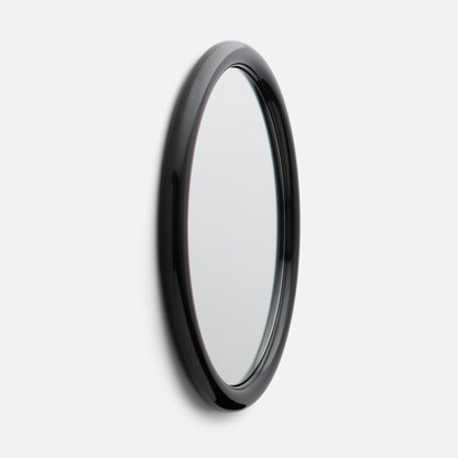 Close-up side view of Forma Mirror showcasing its glossy black rounded frame and beveled edge against a white wall