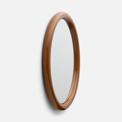 Angled close-up of Forma Mirror showing glossy brown oval frame and beveled mirror edge against white wall