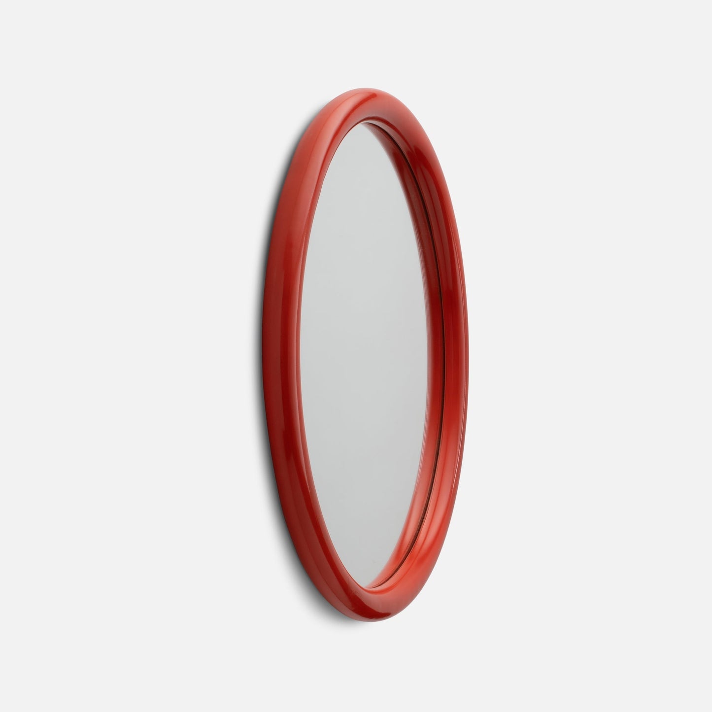 Angled close-up of Forma Mirror showing glossy red rounded frame against a white background