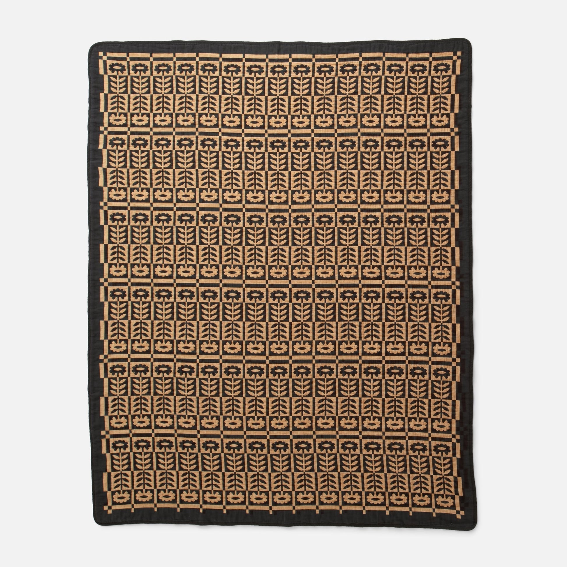 Overhead view of Stillwater Quilt showcasing its mirrored floral jacquard pattern in black and tan on white background