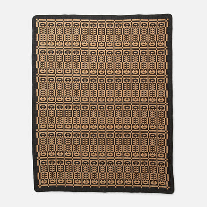 Overhead view of Stillwater Quilt showcasing its mirrored floral jacquard pattern in black and tan on white background