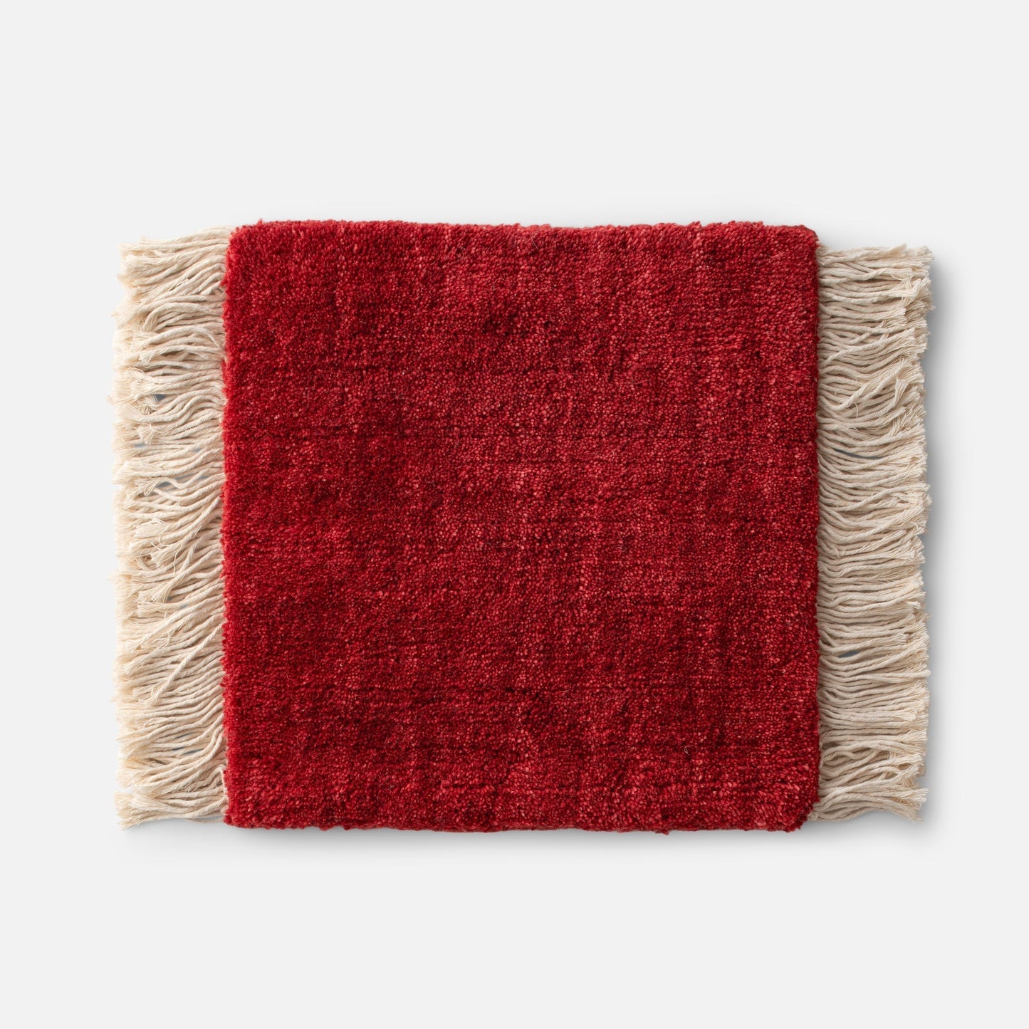 Close-up of Mesa Wool Rug showing hand-loomed red wool cut pile and natural fringe on a white background