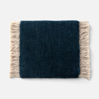 Close-up of Mesa Wool Rug edge showcasing hand-loomed navy wool pile and natural fringe on white background
