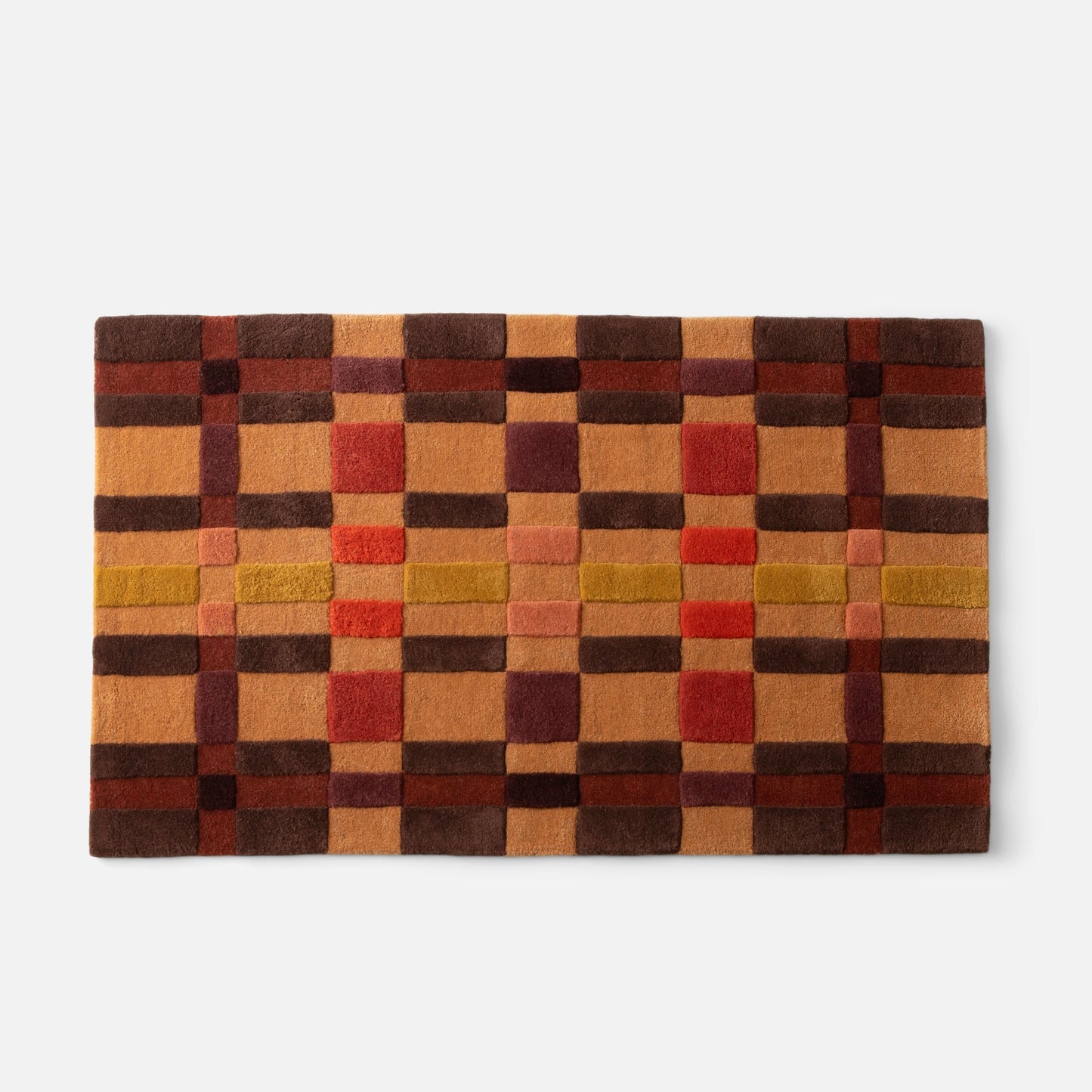 Top edge view of Campus Wool Rug showcasing recessed-pile plaid squares in brown, rust, mustard, and red on white background