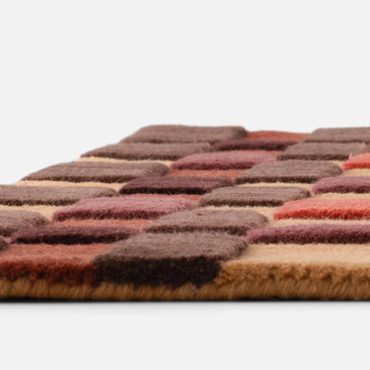 Close-up side view of Campus Wool Rug showcasing recessed wool pile squares in warm brown and rust tones on white background