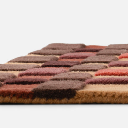 Close-up side view of Campus Wool Rug showcasing recessed wool pile squares in warm brown and rust tones on white background