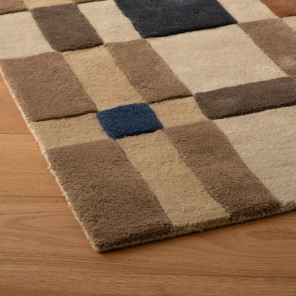Angled close-up of Campus Wool Rug showcasing recessed wool pile and plaid-like check pattern in beige, brown, and navy on a wood floor
