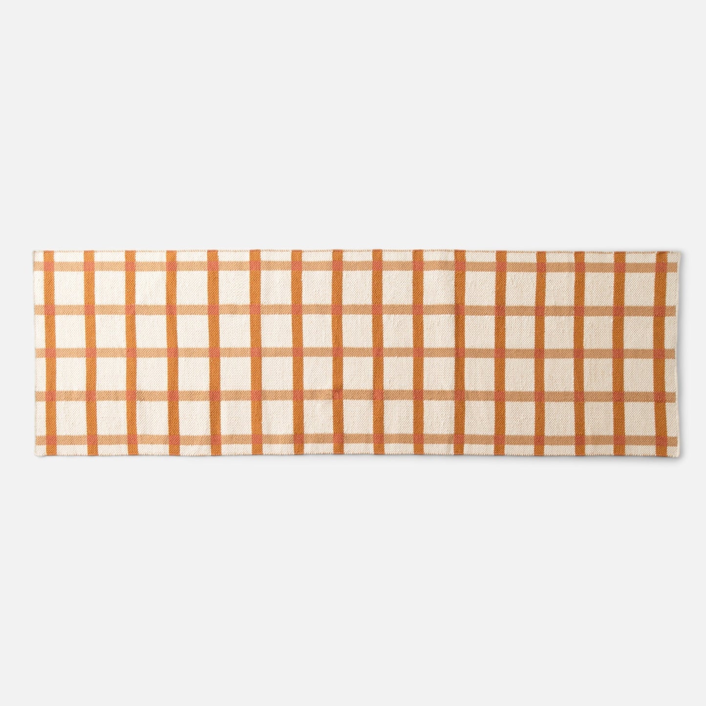 Top-down view of Plaid Wool Reversible Rug showcasing orange-and-beige plaid and handwoven wool texture on a white background