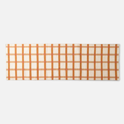 Top-down view of Plaid Wool Reversible Rug showcasing orange-and-beige plaid and handwoven wool texture on a white background