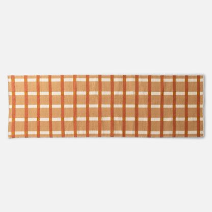 Cropped top edge of Plaid Wool Reversible Rug showing orange, tan, and cream plaid wool weave on white background