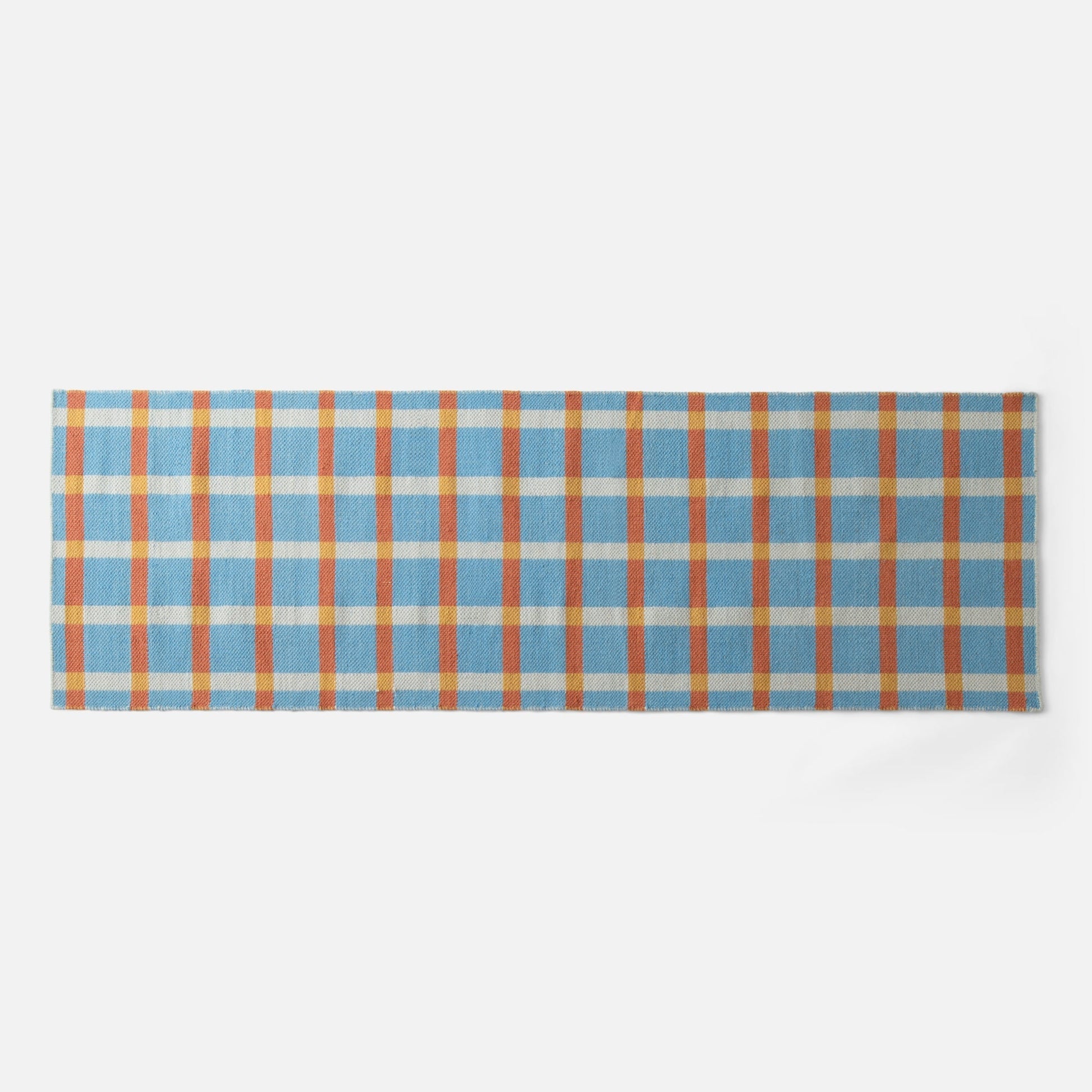 Close-up top-edge view of Plaid Wool Reversible Rug showing blue, orange and yellow plaid on white background