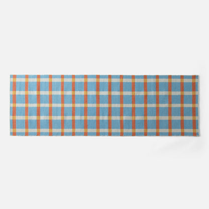 Close-up top-edge view of Plaid Wool Reversible Rug showing blue, orange and yellow plaid on white background