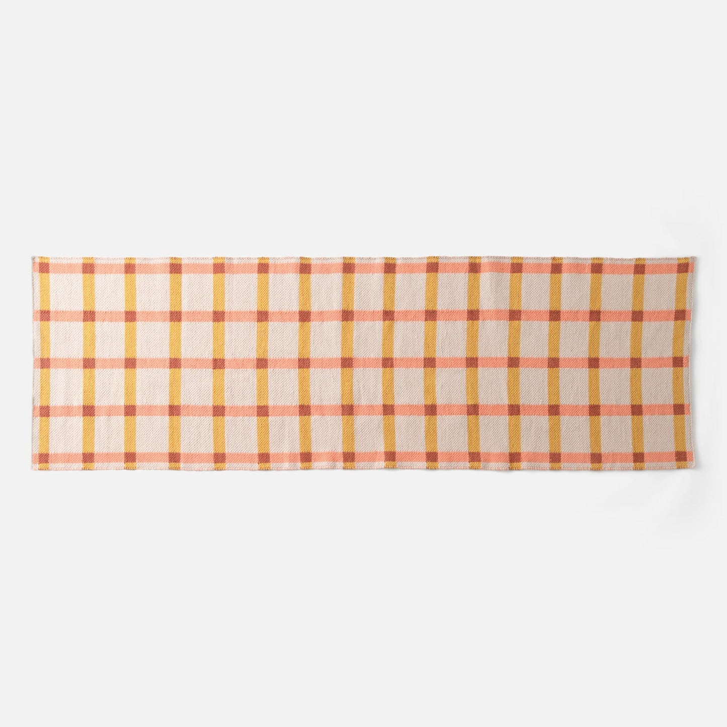 Flat lay of Plaid Wool Reversible Rug showcasing peach, mustard, and rust plaid on a white background
