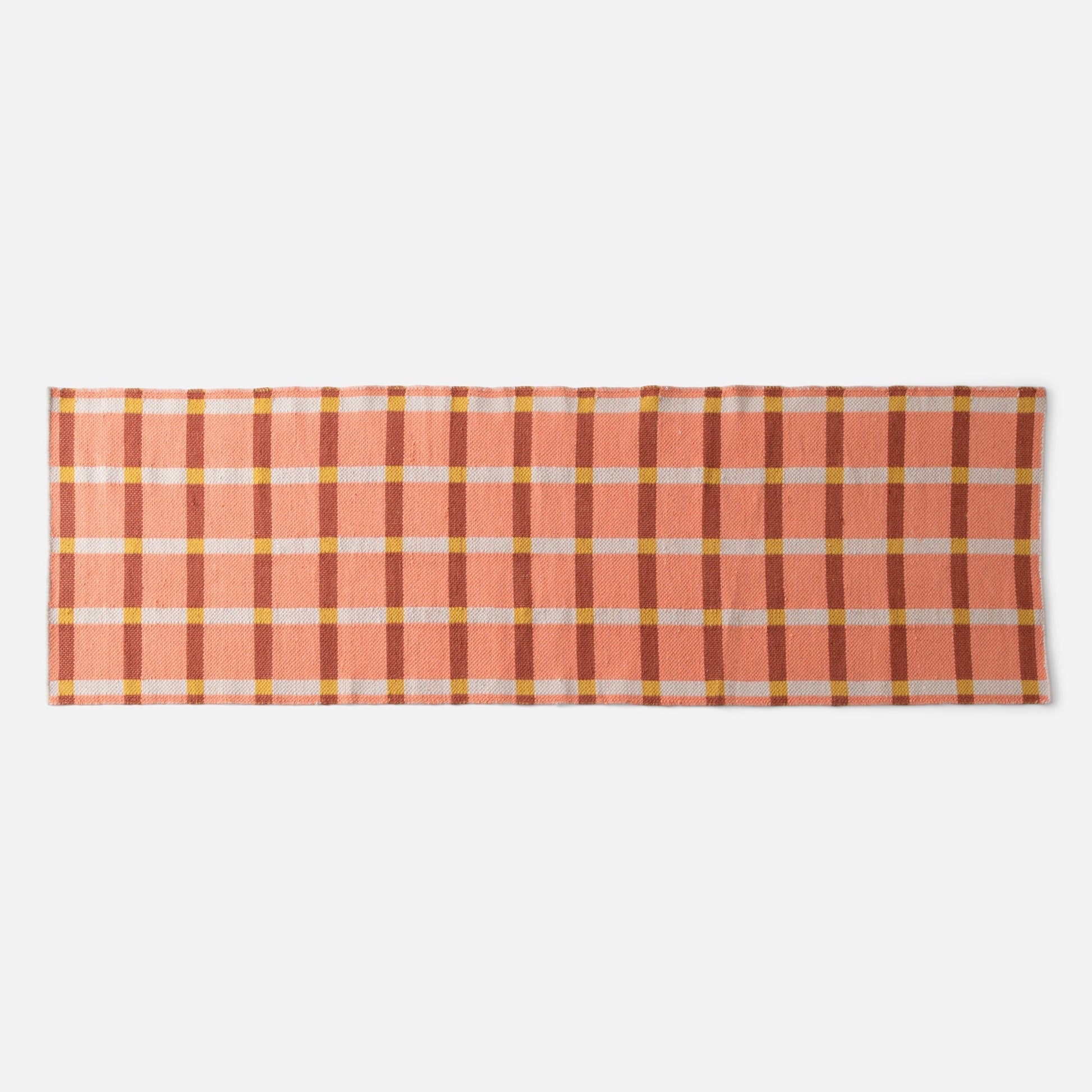 Flat-lay of Plaid Wool Reversible Rug showing peach and rust plaid with yellow and white checks on white background