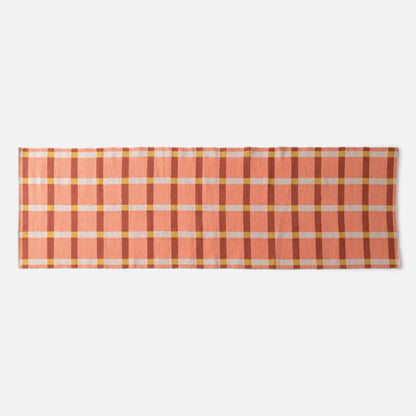Flat-lay of Plaid Wool Reversible Rug showing peach and rust plaid with yellow and white checks on white background
