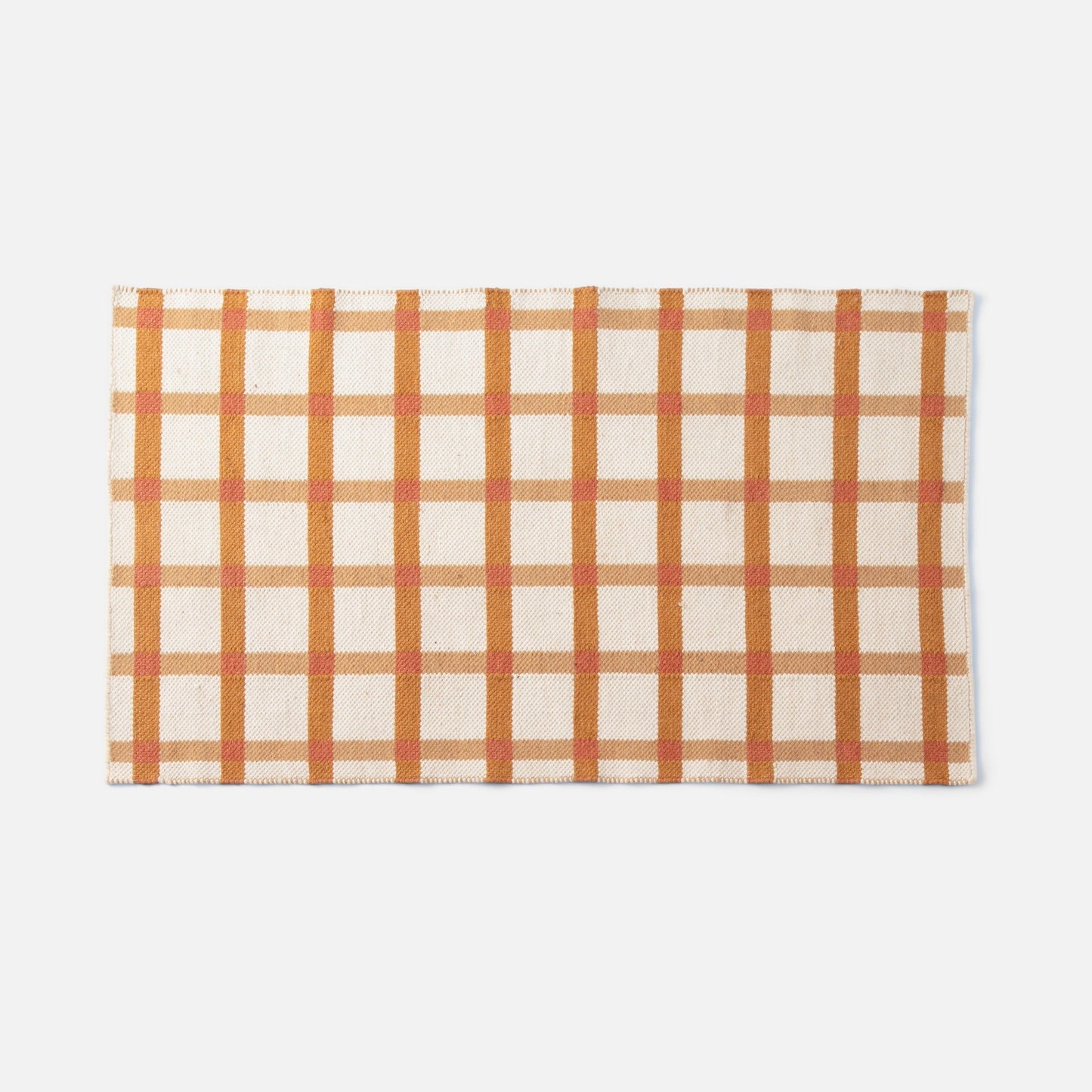 Top view of Plaid Wool Reversible Rug showcasing orange and tan plaid and handwoven wool texture on white background