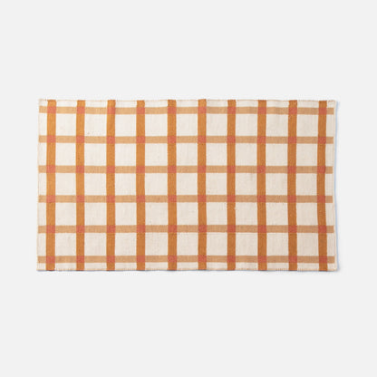 Top view of Plaid Wool Reversible Rug showcasing orange and tan plaid and handwoven wool texture on white background