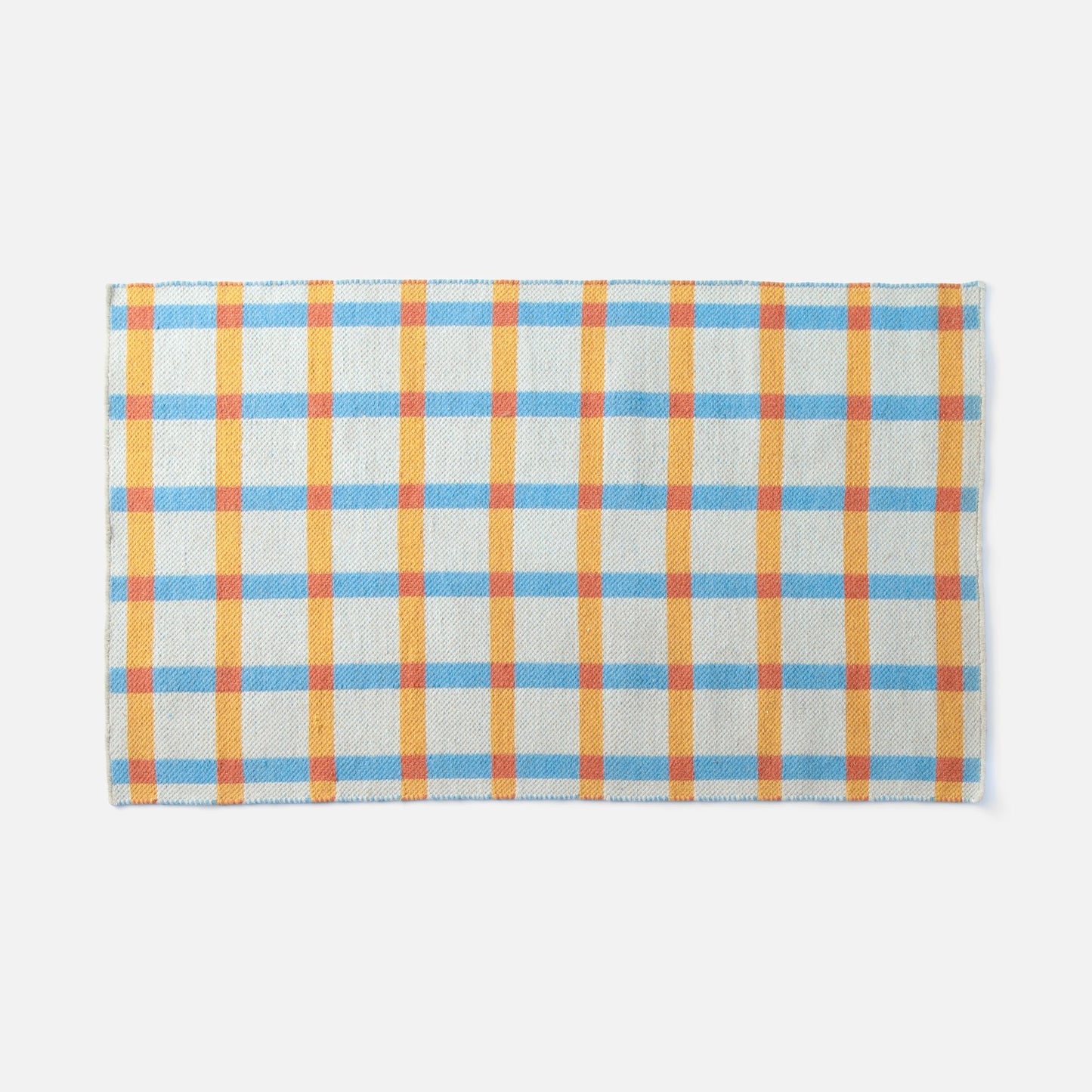 Top-edge view of Plaid Wool Reversible Rug showcasing woven high-contrast blue, yellow, and orange plaid on a white background