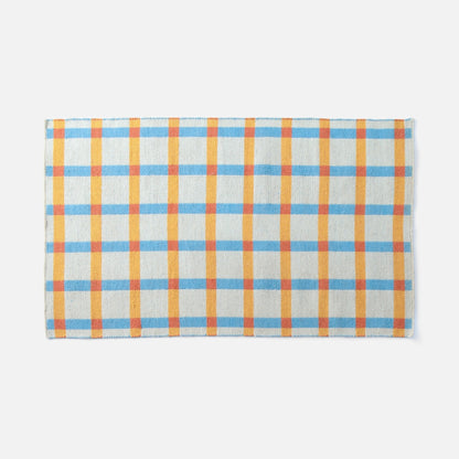 Top-edge view of Plaid Wool Reversible Rug showcasing woven high-contrast blue, yellow, and orange plaid on a white background