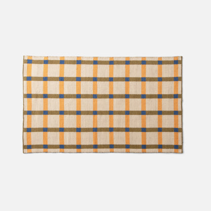 Flat lay of Plaid Wool Reversible Rug showing handwoven plaid in cream, mustard, olive and blue on white background