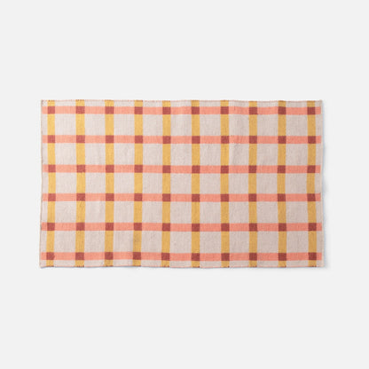 Cropped top view of Plaid Wool Reversible Rug showcasing its reversible weave and pink, yellow, and rust plaid on white background