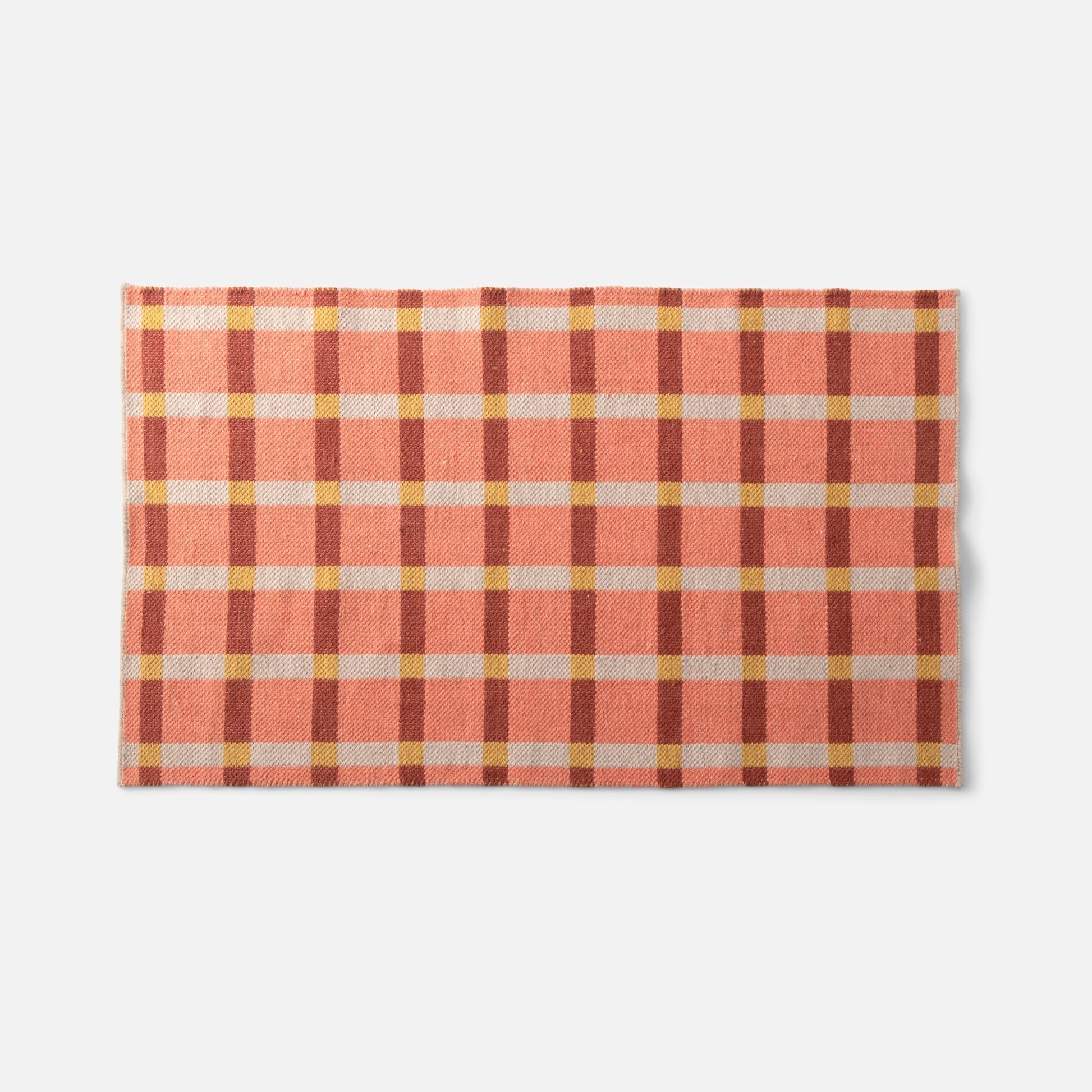 Top view of Plaid Wool Reversible Rug showcasing handwoven peach and cream plaid in natural-dyed wool on a white background