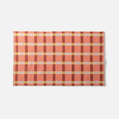 Top view of Plaid Wool Reversible Rug showcasing handwoven peach and cream plaid in natural-dyed wool on a white background