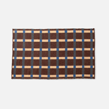 Top-down view of Plaid Wool Reversible Rug showcasing brown, cream and blue high-contrast plaid and woven texture on white background