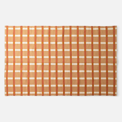 Flat lay of Plaid Wool Reversible Rug showing handwoven natural-dyed wool in orange and tan plaid on white background
