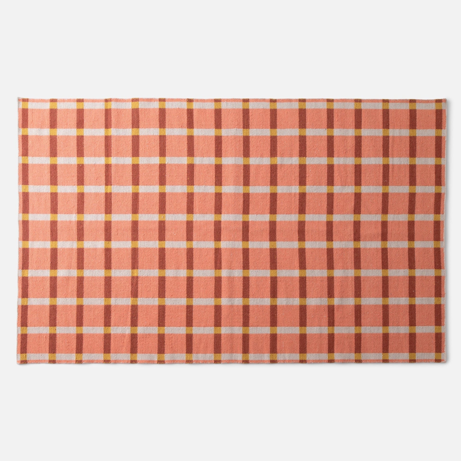 Top-down view of Plaid Wool Reversible Rug showcasing peach-and-rust plaid with white and yellow checks on a white background