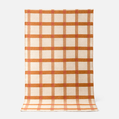 Top-down view of Plaid Wool Reversible Rug showcasing cream wool with rust orange and tan plaid and handwoven reversible texture on light gray background