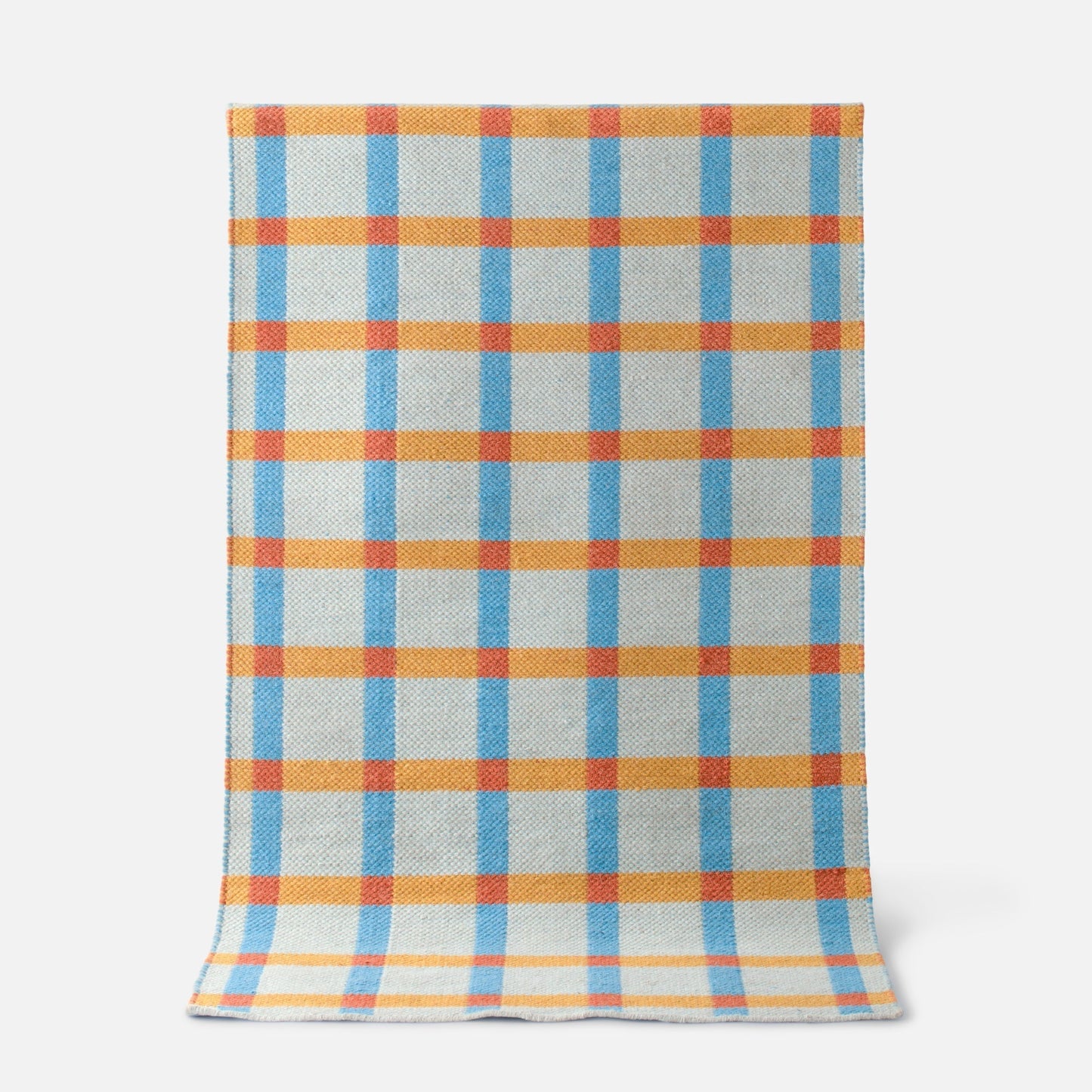Top-down view of Plaid Wool Reversible Rug showing blue and orange high-contrast plaid and woven wool texture on a white background