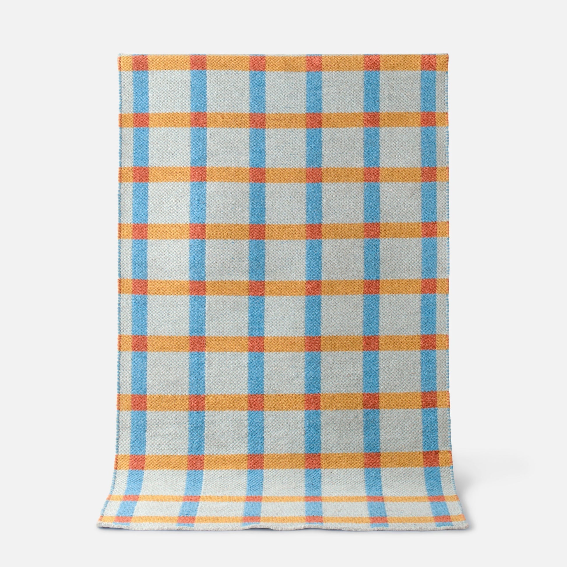 Top-down view of Plaid Wool Reversible Rug showing blue and orange high-contrast plaid and woven wool texture on a white background