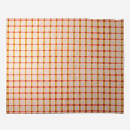 Top-down view of Plaid Wool Reversible Rug showing coral and mustard plaid on a neutral ground with white studio background