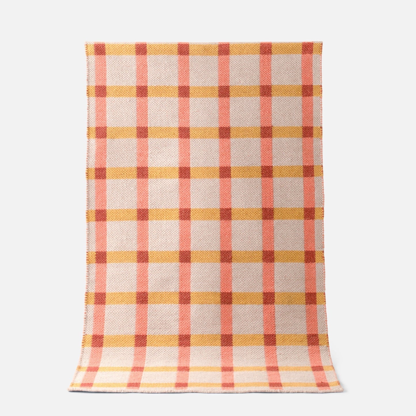 Top-down view of Plaid Wool Reversible Rug showcasing peach and mustard plaid handwoven wool on a white background
